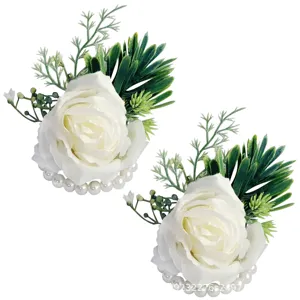 Detailaufnahme von weißen Rosen-Handgelenkkorsagen mit grünen Blättern und Perlen.