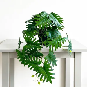 Close-up detail of artificial potted green plant with split leaves on table, natural decor style.