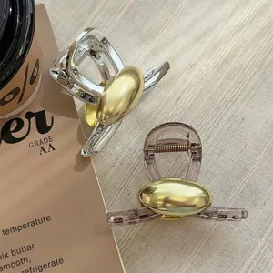 Elegante Haarklammern aus Metall und Kunststoff mit goldenen Ovalen auf stoffähnlichem Grund