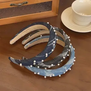 Set di cerchietti in denim decorati con perle e strass su sfondo in legno.