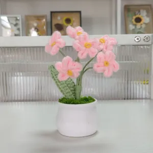 Handmade crochet pink flower potted plant detail showing delicate stitches and green leaves.