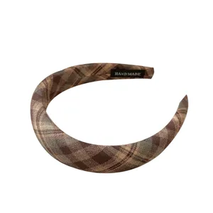 Retro bruine geruite wollen haarband met een handgemaakt label op een strakke witte achtergrond
