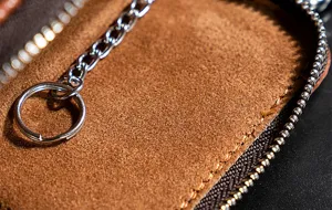 Close-up detail van bruine lederen sleuteletui rits en metalen ring ketting textuur.