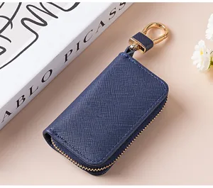 Primo piano dettagliato di un portachiavi in pelle blu scuro con cerniera e gancio dorati.