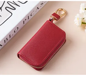 Primo piano dettagliato di un astuccio per chiavi in pelle rossa con cerniera e libro decorativo.