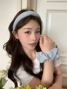 Asiatisches Model trägt ein hellblaues Polka-Dot-Schwamm-Haarband und passendes Scrunchie.