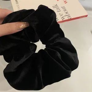 Close-up of a premium black velvet scrunchie showing rich texture and soft sheen