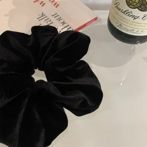 Detailed macro shot of an oversized black velvet scrunchie showing soft pleated texture