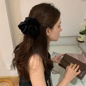 Elegant black velvet scrunchie hair tie worn by a brunette model in a stylish setting