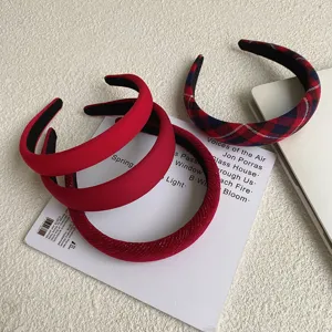 Close-up view of stylish red retro hair headbands in plaid and solid fabric textures