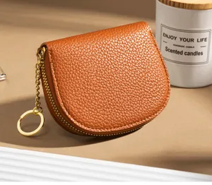 Close-up detail of brown pebbled leather semi-circular coin purse with gold zipper and keychain.
