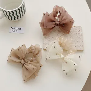 Gros plan sur des chouchous en organza scintillants avec nœuds et strass élégants.