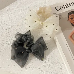 Gros plan sur d'élégants chouchous nœuds en organza à strass en blanc crème et noir