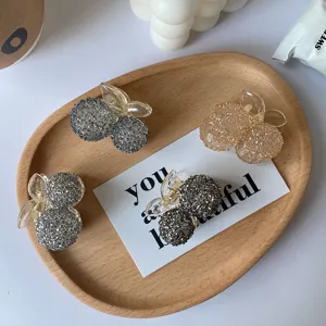 Detailed view of four colorful crystal beaded cherry hair claw clips on a wooden tray