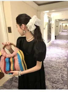 Detailopname van een grote witte kanten mesh scrunchie met stippen op een Aziatisch model.