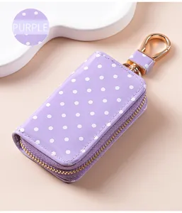 Kompaktes lila gepunktetes Leder-Etui für Autoschlüssel mit goldenem Reißverschluss und Haken.