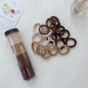 Detail shot of elastic hair ties in neutral earth tones with a clear storage tube.