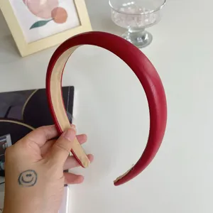 Detail view of a red padded headband with smooth texture and elegant high-top design.