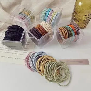 Detail showing twisted texture and colors of milk tea elastic hair ties in boxes
