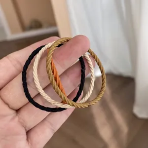 Close-up of elastic hair ties in milk tea colors with spiral texture held by hand