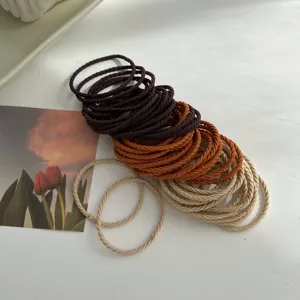 Detailed view of braided elastic hair ties in a range of earth-tone milk tea colors