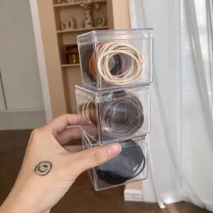 Close-up of three stacked transparent boxes with milk tea colored elastic hair ties