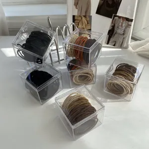 Detailed view of neutral milk tea colored elastic hair ties in clear acrylic boxes