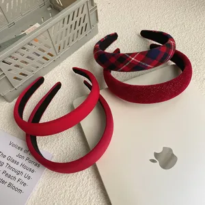 Close-up of vintage red Christmas headbands with plaid and velvet textures on desk