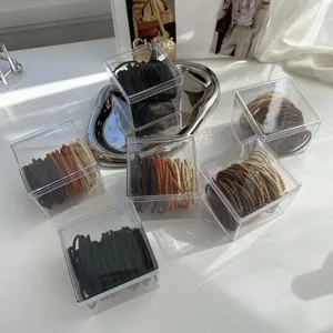 Close-up of various hair ties in milk tea shades stored in transparent plastic boxes.