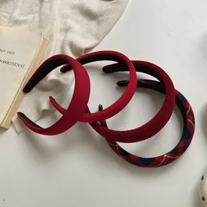 Close-up detail of three festive red headbands in matte, glitter, and plaid styles