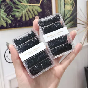 Close-up detail of black elastic hair ties in a clear plastic compartmentalized box