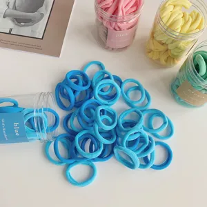 Close-up detail of blue elastic hair ties scattered on a white surface with box packaging