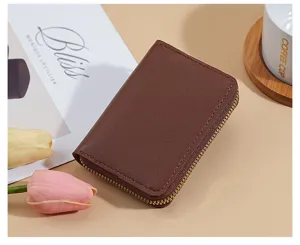 Primo piano dettaglio di un porta carte in pelle marrone con chiusura lampo su sfondo neutro.
