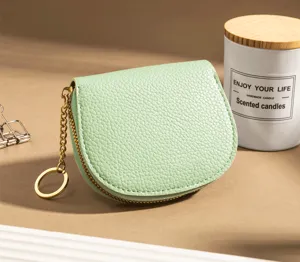 Detailed shot of mint green leather coin purse, gold zipper and keychain close-up.