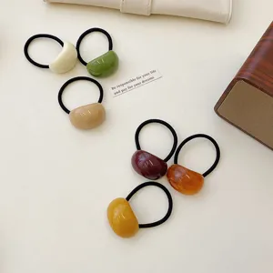 Detail view of colorful minimalist acrylic jelly hair ties in various earthy tones.