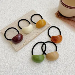 Close-up of colorful jelly acrylic hair ties arranged on a minimalist textured background
