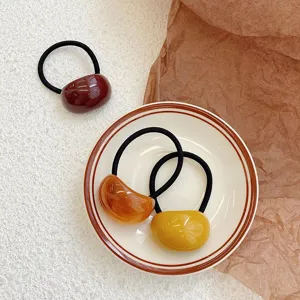 Detail view of minimalist acrylic jelly hair ties in warm autumnal colors on a plate