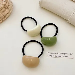 Detail view of three minimalist acrylic jelly hair ties in cream, green and tan colors