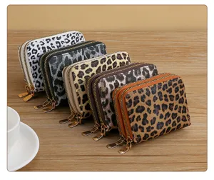 Detailed view of short double-zipper leopard print coin purses and card holders with metal hardware.