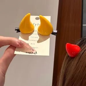 Detalle de pinzas para el cabello con cuernos de diablo amarillas y rojas para Halloween