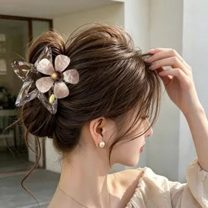 Elegante Haarspange aus Acetat mit Blumen und Sternen an einer Dutt-Frisur.