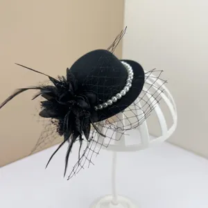 Detail view of a black vintage fascinator with mesh veil, feathers, and pearl accents.