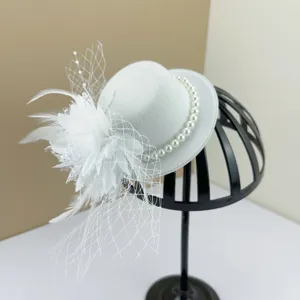 Detail shot of a vintage white fascinator hat with feathers, mesh veiling and pearls