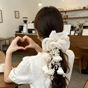 Elegant Bohemian white floral hair scrunchie with hanging tassels on a model's hair
