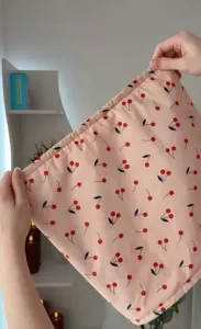 Detail showing the elastic band and cherry pattern of a pink waterproof shower cap