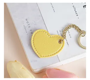 Detail view of a cute yellow heart leather keychain with gold metal chain and ring for bags.