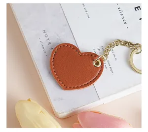 Close-up detail of a cute brown heart leather keychain with gold metal chain and ring.