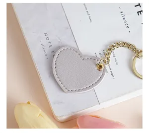 Light grey heart leather keychain close-up detail, cute bag charm and car key holder.