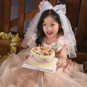 Detailed view of child's princess veil with colorful pompoms and large mesh bow