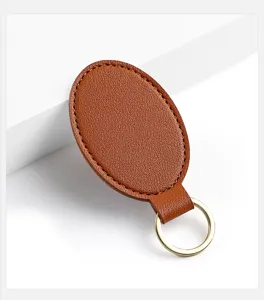 Primer plano detalle llavero de cuero pu marron ovalado con anillo metalico elegante util